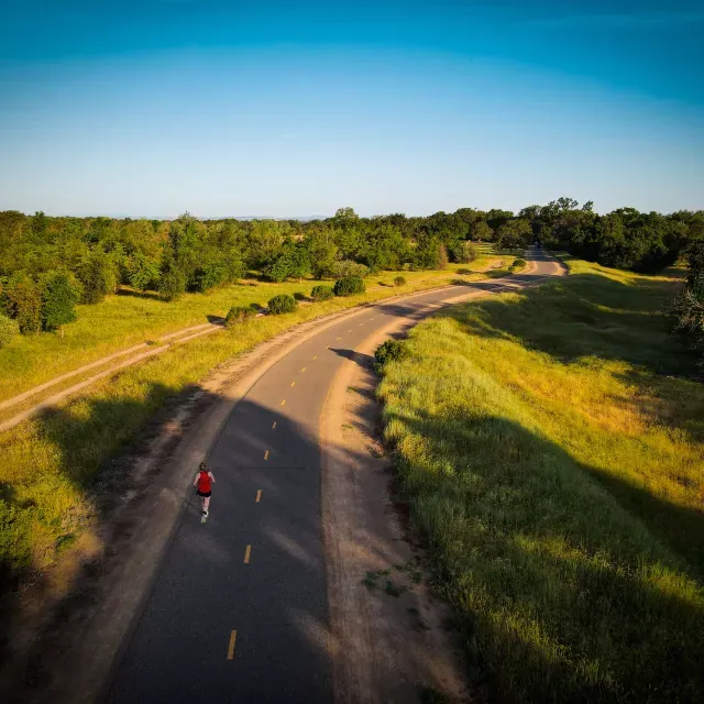 Overhead shot of woman running on a road through the countryside